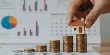 Hand placing model house on coins, symbolizing financial impact of Fed rate hike